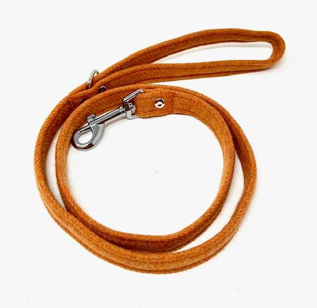 orange tweed dog leash with a metal clip on a white background