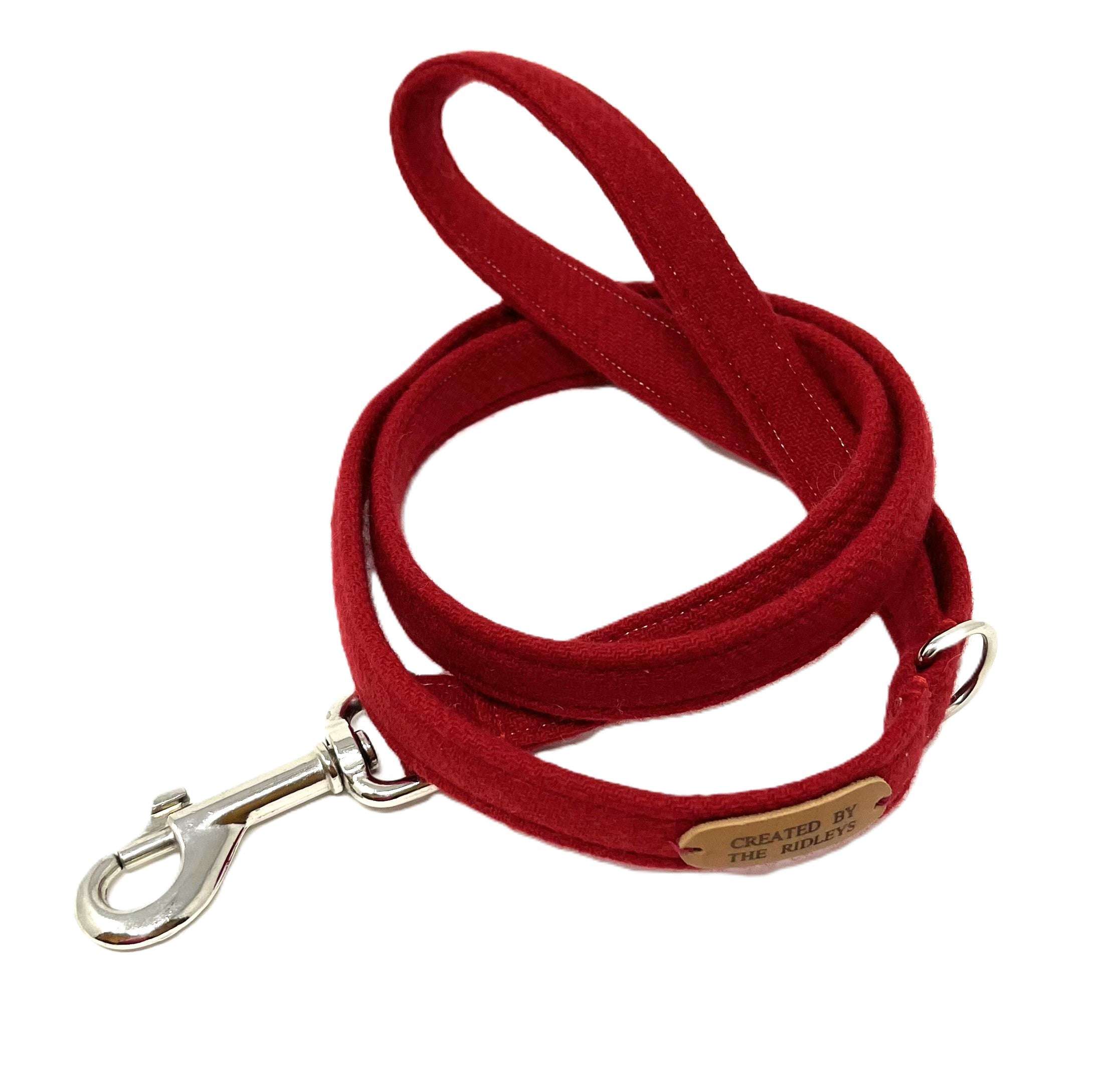 Red dog leash with metal clip and engraved tag on a white background